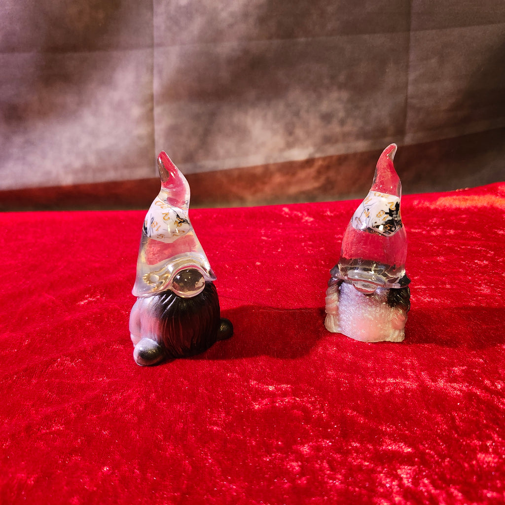 A matching two-piece set of handcrafted 3D resin fantasy luck gnomes featuring crystal-clear pointed hats with real polyhedral D20 gaming dice suspended inside.